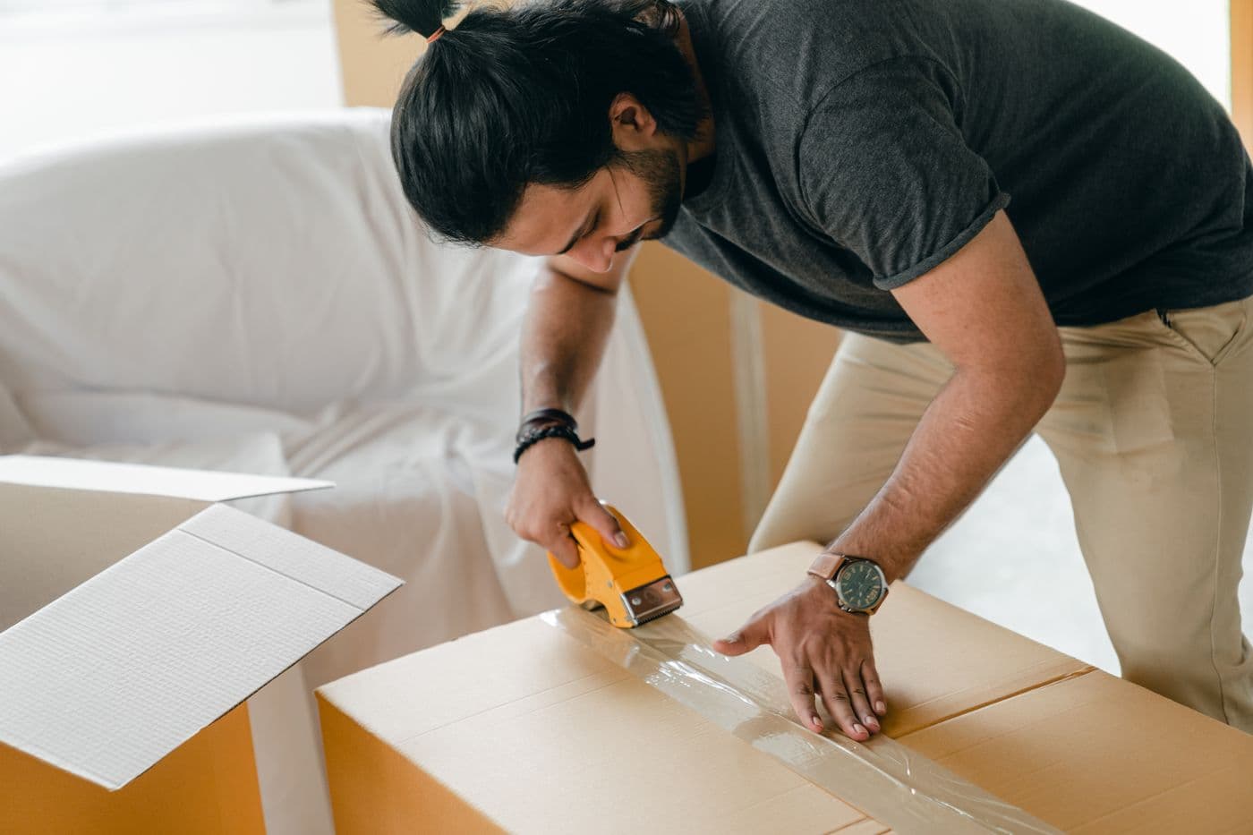 A person carefully sealing a cardboard moving box